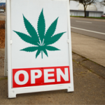 Cannabis store sidewalk sign with image of leaf and word OPEN