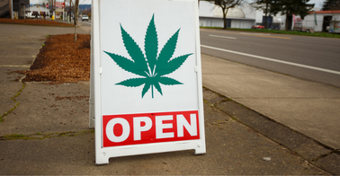 Cannabis store sidewalk sign with image of leaf and word OPEN