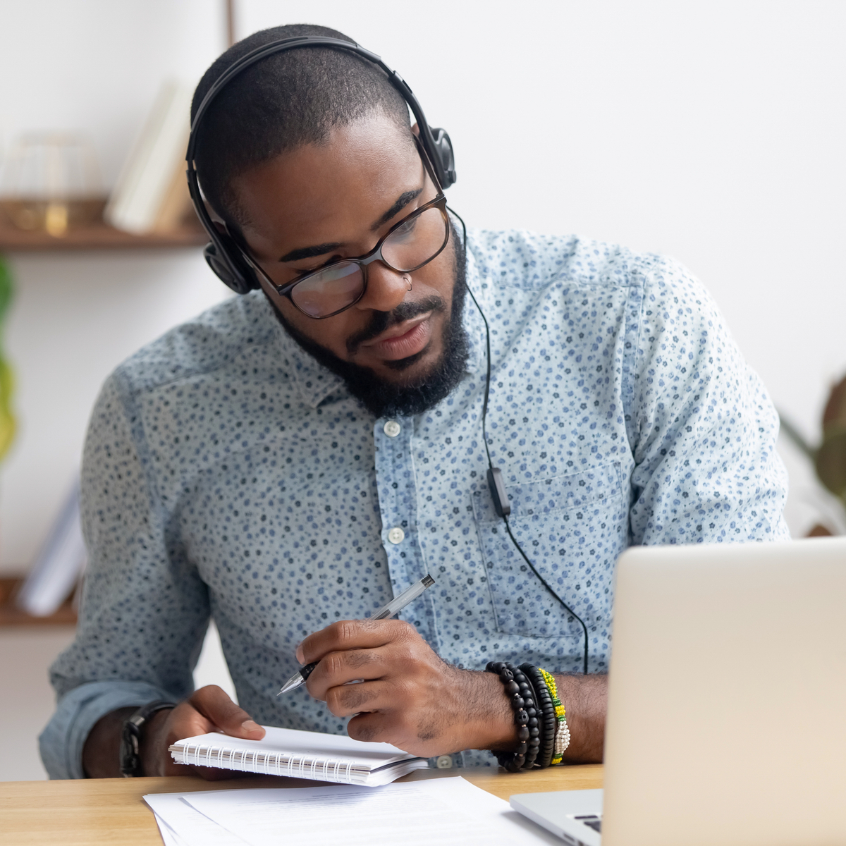 Man looking at laptop and taking notes