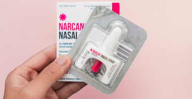 Hand holding a nasal narcan kit