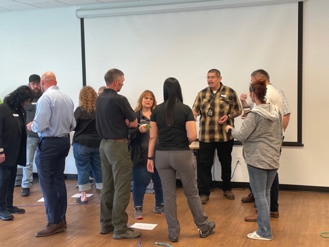 Group of people standing in front of a projector screen talking in small groups