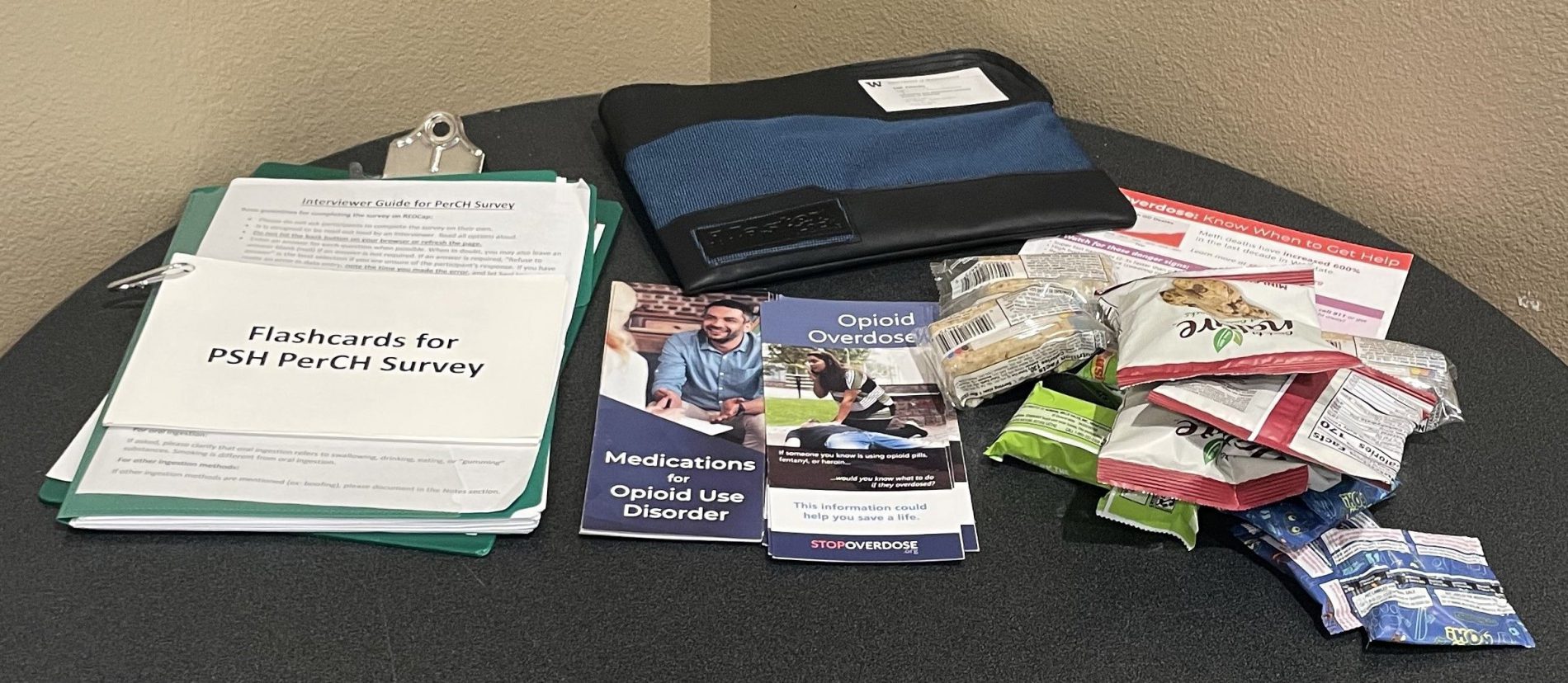 Table with items from the PerCH survey, including clipboard, brochures, and snacks