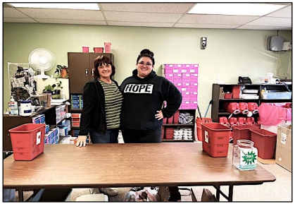 Two women standing at a table smiling inside an SSP. One woman's shirt reads HOPE.