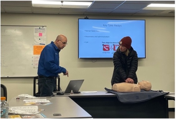 Two people in front of a screen at a training.
